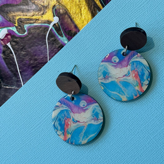 Colorful abstract teardrop earrings with wooden accents on a blue background