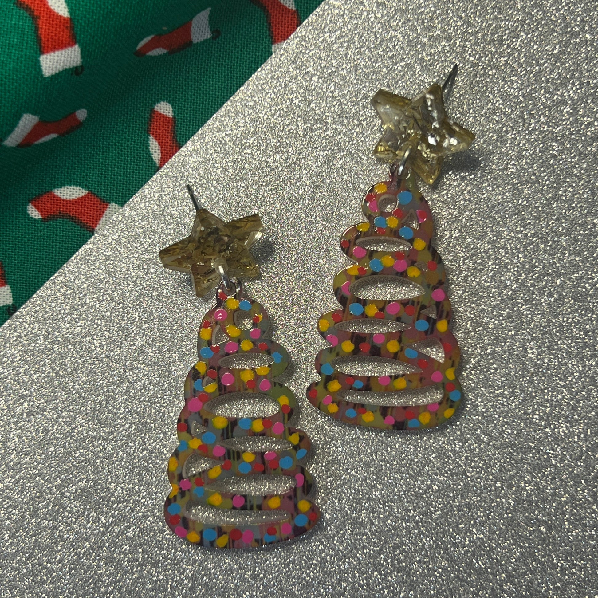 Colorful beaded earrings with star accents on a glittery surface.