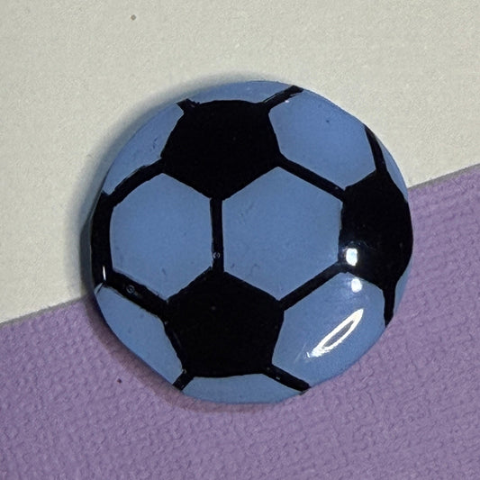 Soccer ball magnet in Blue and Black. On white and purple background. 