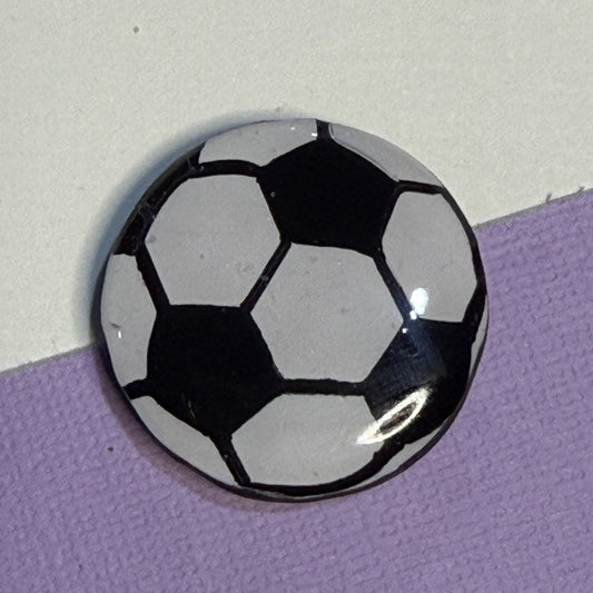 Soccer ball magnet, white and black colour. On white and purple background